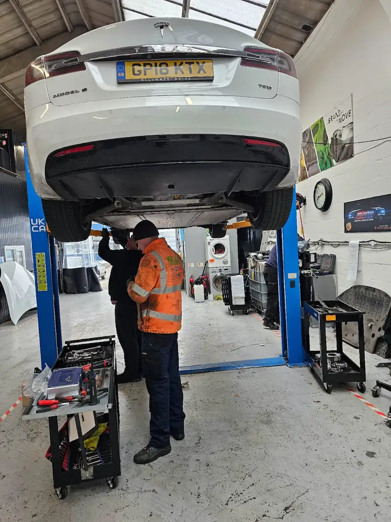 technicians-inspecting-a-tesla-model-s-underneath-on-a-lift