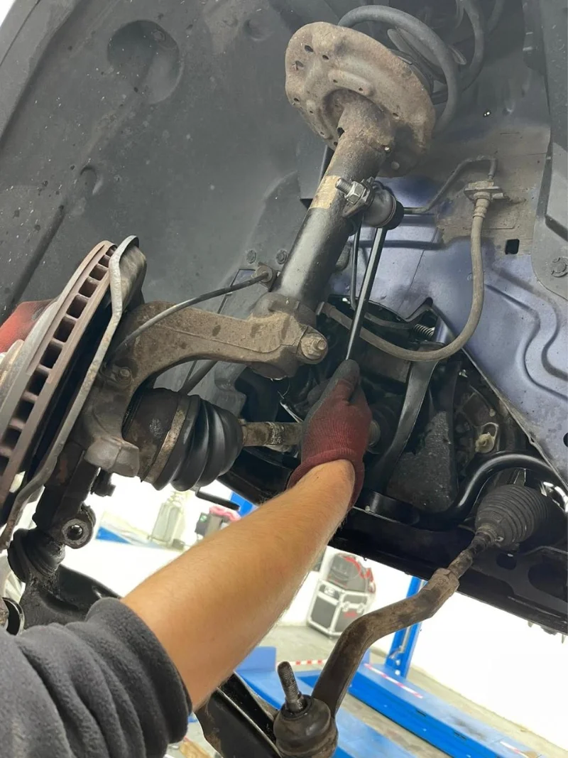 AutoNet-VIP-mechanic-working-on-a-vehicle-suspension-and-wheel-assembly-inside-the-garage