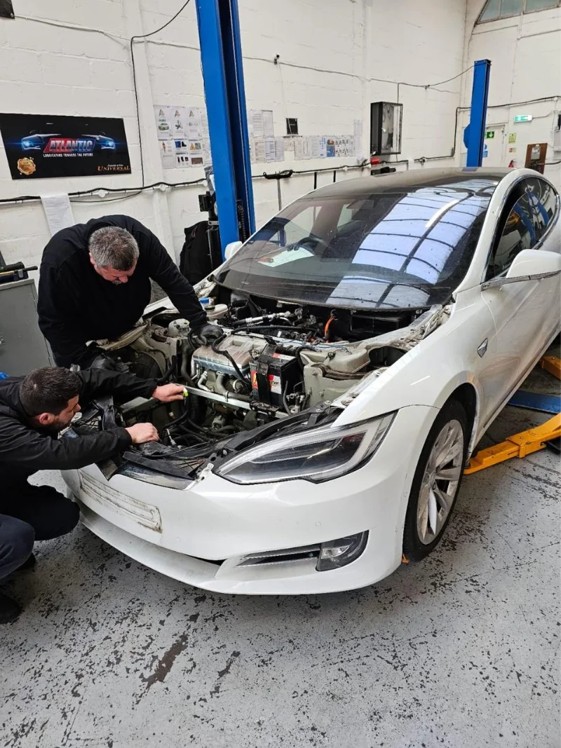 AutoNet-VIP-mechanics-carrying-out-repair-work-on-a-white-electric-vehicle-inside-the-workshop
