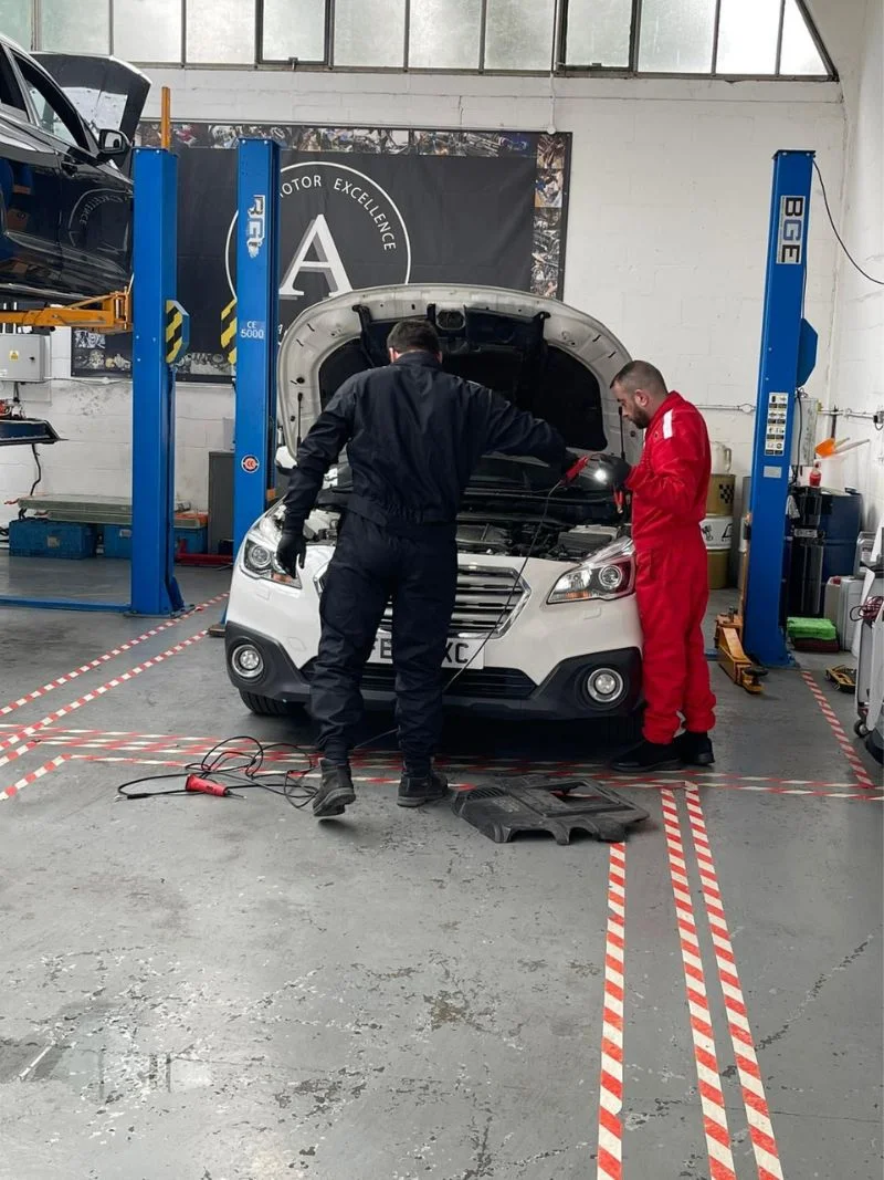AutoNet-VIP-mechanics-inspecting-and-repairing-a-white-vehicle-with-the-bonnet-open-inside-the-garage-1