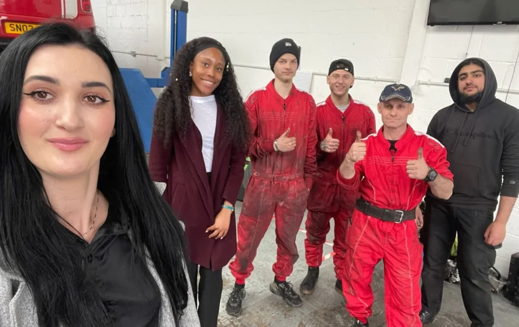 AutoNet-VIP-team-standing-together-inside-the-car-repair-garage-with-team-members-wearing-red-work-overalls-and-giving-thumbs-up