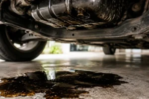 Engine-Oil-Light-caused-by-potential-oil-leak-showing-dark-engine-oil-dripping-underneath-a-car-requiring-maintenance-check